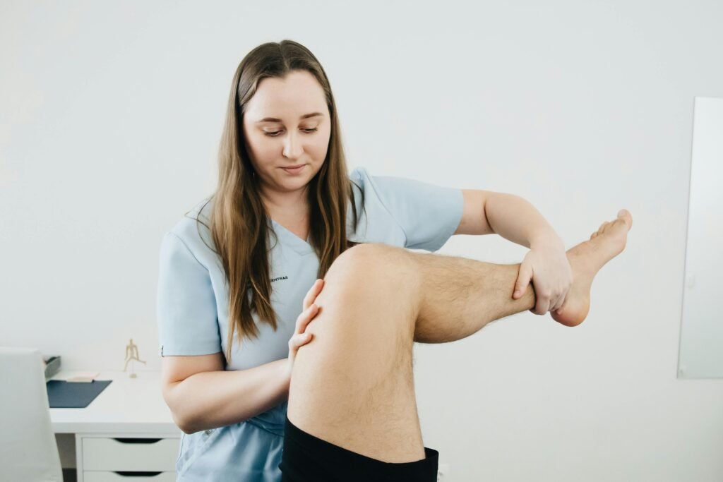 A physiotherapist assisting a patient's leg therapy session indoors, focusing on rehabilitation.