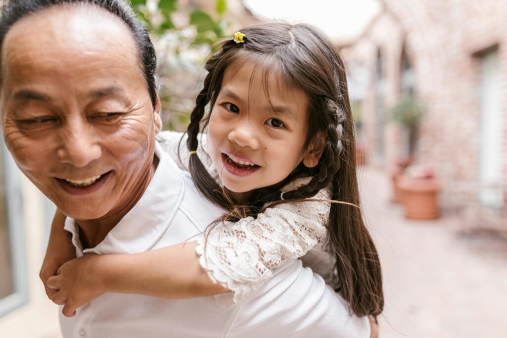 Happy girl enjoying a fun piggyback ride with her grandparent in an outdoor setting.