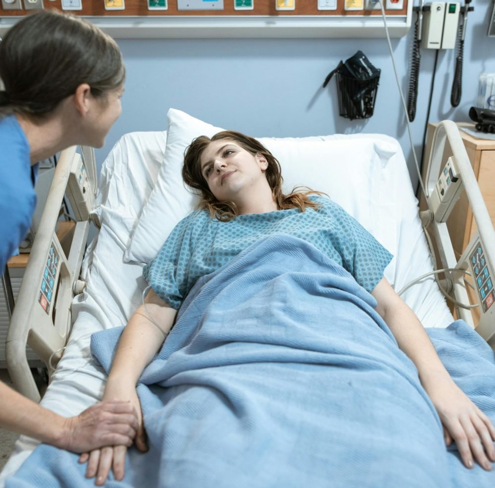 A nurse compassionately holds a patient's hand in a hospital room setting, promoting care and support.
